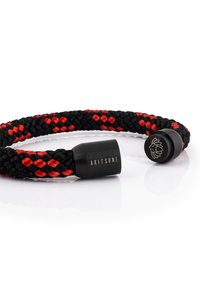 Bracciale intrecciato in corda nera e rossa, con estremità in metallo nero dotate di logo e nome del marchio incisi. Aspetto liscio e texturizzato.