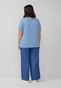 Hellblau gestreiftes T-Shirt mit kurzen Ärmeln, kombiniert mit locker sitzenden blauen Jeans. Einfaches Design und lässige Passform, minimale Details.