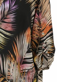 Schwarzer Stoff mit buntem Palmenblattmuster in Orange, Pink und Creme. Verfügt über ein Knopfdetail am Ärmel und einen lockeren Schnitt.