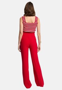 Pantalones rojos de pierna ancha combinados con una blusa sin mangas a rayas rojas y blancas. Las telas parecen suaves, con un ajuste ceñido en la cintura.