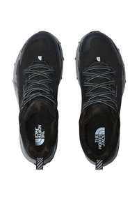 Zapatos deportivos negros con parte superior de malla, acentos reflectantes, suela de goma gris y tirador a rayas. El interior presenta el logotipo en gris.