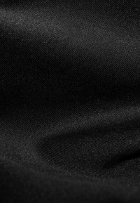 Tessuto nero con una superficie liscia, caratterizzato da una leggera lucentezza e un delicato motivo di trama. Il materiale appare leggero e flessibile.