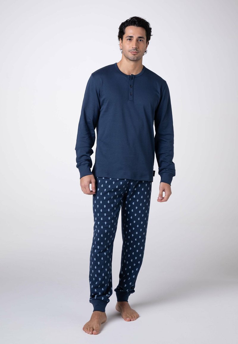 Maglietta henley a maniche lunghe blu navy con tre bottoni, abbinata a pantaloni blu navy con motivi di cavallucci marini azzurri e polsini elasticizzati.