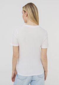 T-shirt bianco a maniche corte, leggero, con scollatura rotonda e bordi delle maniche bianchi a contrasto. Texture liscia.