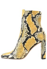 Bottine à imprimé python jaune et noir avec un bout pointu, un talon bloc haut et une surface en cuir texturée présentant des motifs semblables à ceux d'un serpent.