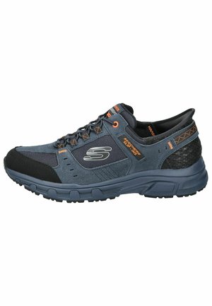 Męskie buty slip-on Skechers, cechujące się ciemnoniebieskim zamszowym i siateczkowym wierzchem, szarymi akcentami, czarną gumową podeszwą oraz teksturowanym tyłem dla wsparcia.