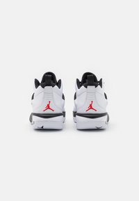 Bílé a černé sportovní boty s červenými akcenty, s hladkým svrškem, polstrovanou podešví a zadním logem Jumpman.