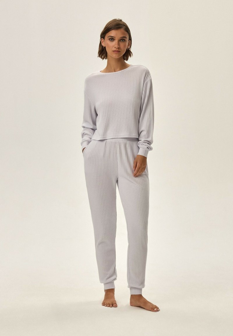 Jasnoszary, prążkowany zestaw odzieży do wypoczynku z długimi rękawami, elastycznym pasem i spodniami zakończonymi mankietami. Miękka faktura, minimalistyczny design, luźny krój.