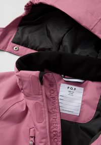 Roze waterdichte jas met een zachte zwarte voering, voorrits en labels binnenin. Heeft het merk "P.O.P WEATHERPRO" geborduurd aan de zijkant.