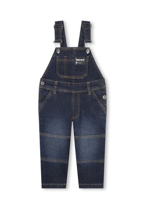 Salopette en denim bleu foncé avec bretelles réglables, poche avant et coutures jaunes contrastées. Présente des fermetures à boutons et des jambes fuselées.