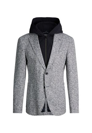 Blazer gris texturé porté par-dessus une veste à capuche noire zippée, combinant styles formel et décontracté.