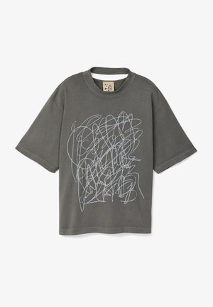 Grå bomuld t-shirt med løs pasform, der har et skriblet hvidt grafisk design på fronten og en ribbet rund halsudskæring.