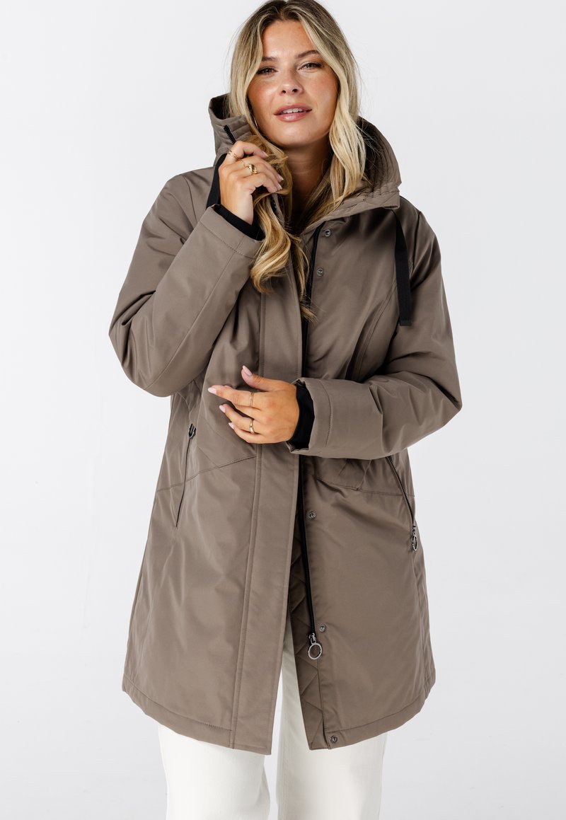 Bruine waterdichte parka met capuchon, voorzien van een ritssluiting, zijzakken en verstelbare trekkoorden. Gemaakt van een gladde, duurzame stof.