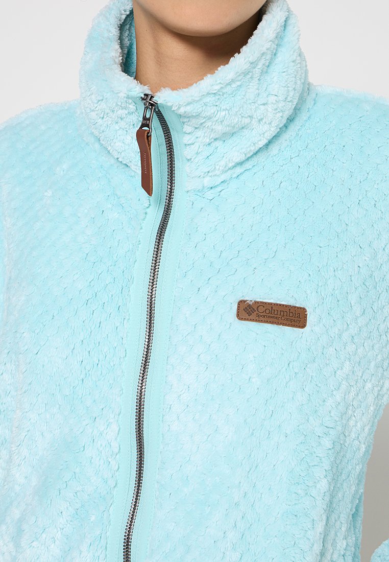 Veste en polaire bleu clair avec une surface texturée et douce. Dotée d'une fermeture éclair frontale intégrale et d'un écusson en cuir marron avec le nom de la marque.
