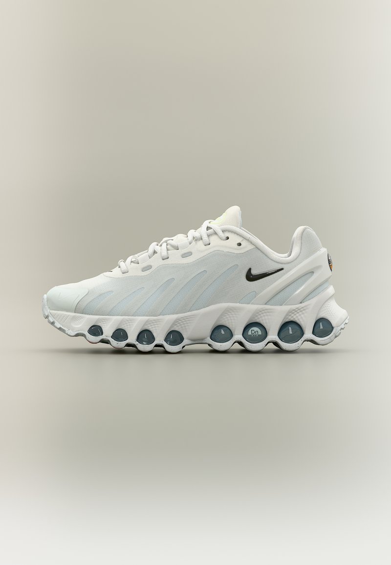 Λευκό παπούτσι τρεξίματος Nike με μαύρο λογότυπο, άνω μέρος από διαπνέον πλέγμα και μοναδική ενισχυμένη σόλα με κυκλικά αεροθαλάμια.