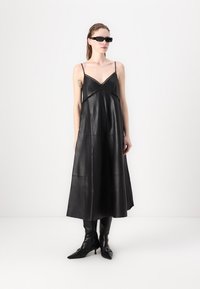 Schwarzes Leder-Maxi-Kleid mit verstellbaren Spaghettiträgern. Verfügt über ein schichtetes Design und dekorative Aussparungen am Ausschnitt.