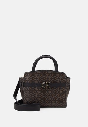 Kleine braune Handtasche mit wiederholtem CK-Logomuster, schwarzen Griffen, einem vorderen Riemen mit goldener CK-Schnalle und einem abnehmbaren schwarzen Schulterriemen.