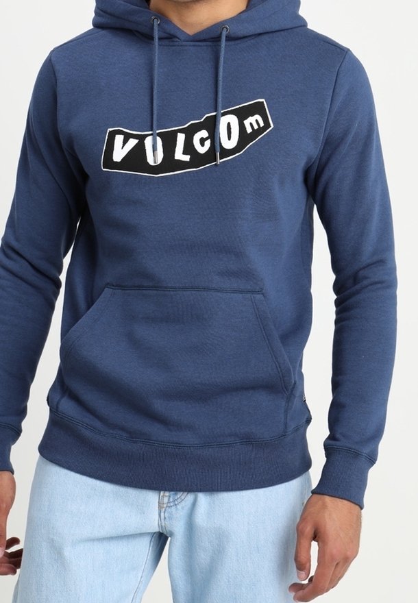 Sudadera de color azul marino hecha de una tela suave, con un bolsillo tipo canguro y un logotipo gráfico en blanco de "VOLCOM" en la parte frontal. Mangas largas y dobladillo acanalado.