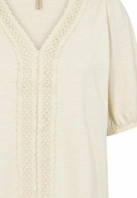 Helebeež blouse V-kaelusega, puffhunnikute varrukatega ja esiosas detailse pitsilõikega. Pehme tekstuur, igapäevane stiil.