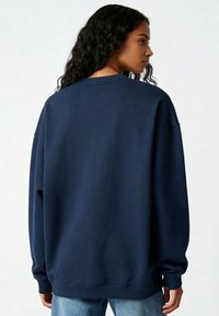 Marineblauwe oversized sweatshirt met een ronde hals, geribde manchetten en onderrand; zachte stoftextuur. Van achteren gezien, met een eenvoudig ontwerp.