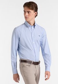 Camicia a righe blu chiaro con colletto button-down, maniche lunghe e logo ricamato. Si abbina a pantaloni beige e cintura marrone.