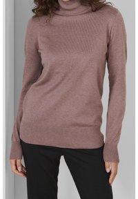 Pullovertrui in zacht mauve breiwerk, voorzien van een opstaande kraag, geribde boorden en zoom. Gecombineerd met zwarte broeken voor een casual look.