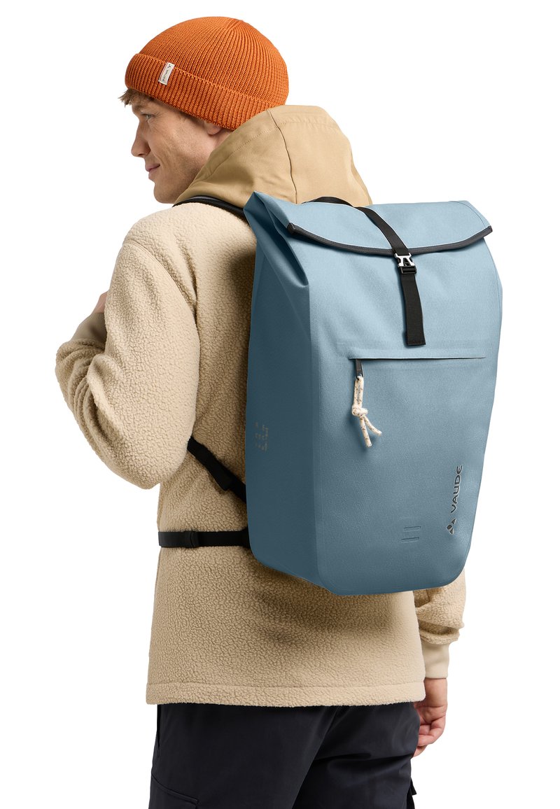 Sac à dos bleu à rabat avec des accents noirs, fabriqué en matériau durable. Doté d'une poche avant et de bretelles ajustables pour le confort.