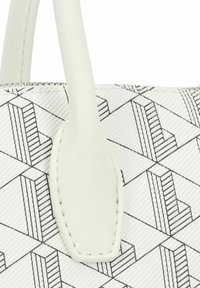 Sac blanc avec un motif de lignes noires géométriques, comportant des poignées en cuir lisse et une fermeture éclair. Matériau texturé avec des détails de design clairs.