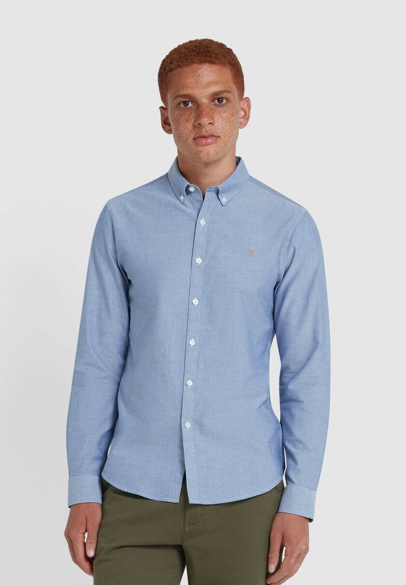Camicia azzurra chiara in tessuto chambray, con colletto, maniche lunghe e un piccolo logo ricamato sul petto.