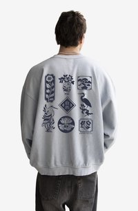Light grey sweatshirt with loose fit, featuring blue graphic designs of plants and birds on the back, textured fabric, ribbed cuffs.