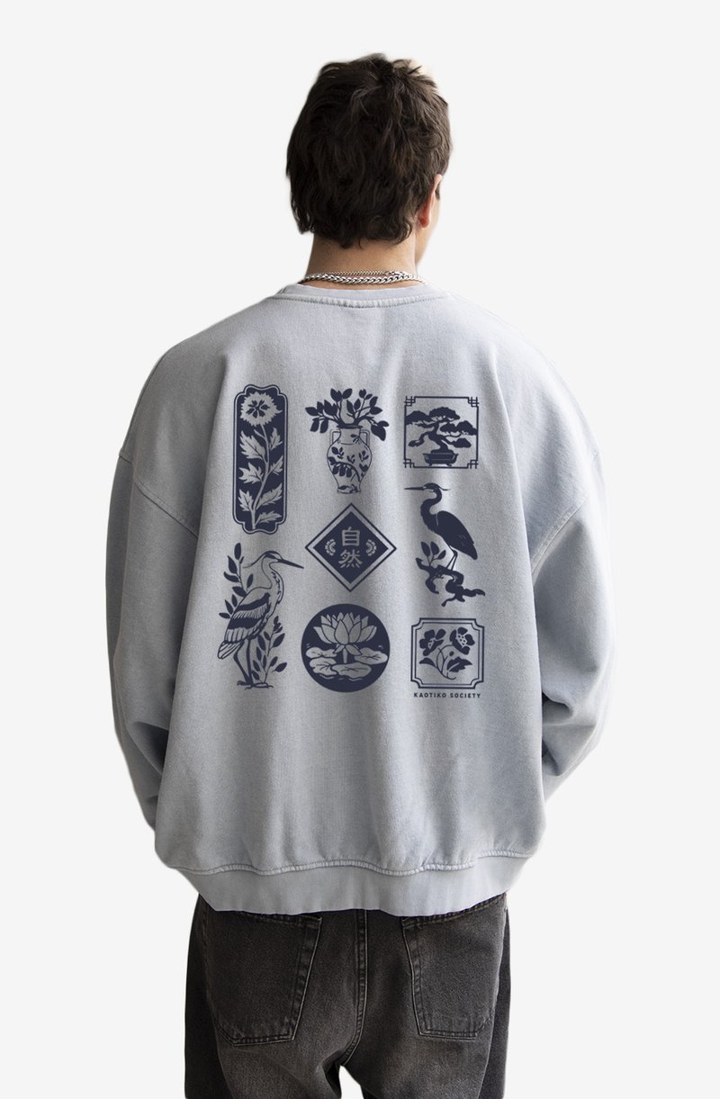Light grey sweatshirt with loose fit, featuring blue graphic designs of plants and birds on the back, textured fabric, ribbed cuffs.
