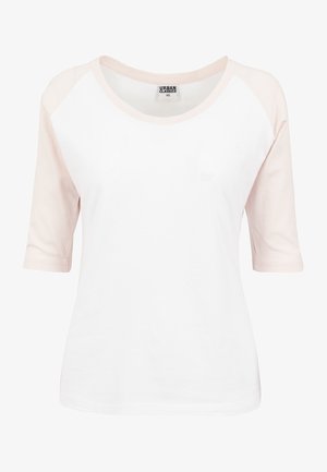 Bílý top s krátkým rukávem a světle růžovými raglánovými rukávy, kulatým výstřihem a měkkou bavlněnou texturou. Štítek říká "URBAN CLASSICS XS."