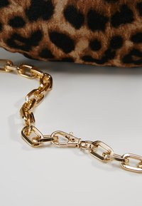 Tessuto con stampa leopardata con tracolla in metallo dorato composta da anelli ovali e una chiusura a moschettone.