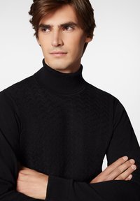 Czarny sweter z golfem z teksturowanym wzorem z przodu, ściągaczami na rękawach i kołnierzu, dopasowanym krojem oraz gładką tkaniną.