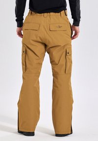Bruine waterdichte cargobroek met een relaxte pasvorm, twee achterzakken en zijzakken. Inclusief ritsen bij de onderbenen.