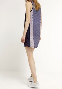 Šaty bez rukávů s námořnickou modrou základnou a světle růžovým geometrickým vzorem po stranách, hladká textura a volný střih.