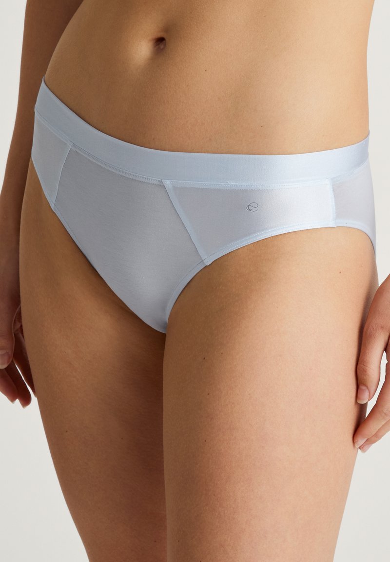 Lichtblauwe damesonderbroek van gladde stof, met een zachte tailleband, klassieke snit en minimale stikseldetail aan de voorkant.