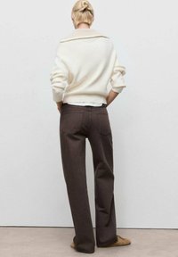 Chunky cream knit sweater with rolled collar paired with high-waisted dark brown wide-leg pants. Soft texture and relaxed fit.