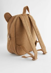 Hnědý kordurových batoh zaobleného tvaru, ušima medvěda, s detailem na zip a nastavitelné popruhy. Texturovaná tkanina a minimalistický design.