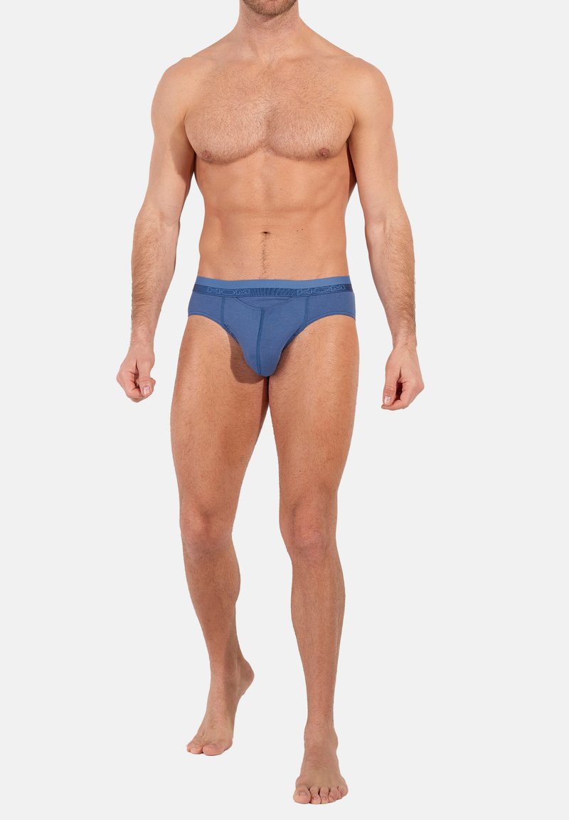 Blaue Baumwollunterhosen mit enganliegendem Design, elastischem Bund mit Logo-Detail und glatter Textur, präsentiert auf einem nackten Oberkörper.