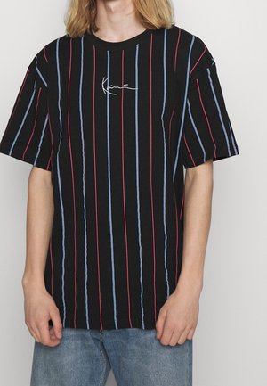 Sort t-shirt med røde og blå lodrette striber, korte ærmer og et lille hvidt grafisk logo på forsiden. Afslappet bomuldsstof.