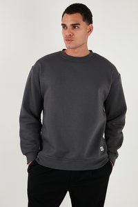 Sudadera gris hecha de material suave, con cuello redondo, mangas largas y una pequeña etiqueta de marca en el costado.