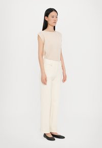 Beige ribbed top with cap sleeves, paired with cream wide-leg trousers and black flats. Simple design, soft texture, and neutral colors.