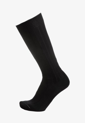 Calza a coste nera mostrata in posizione verticale con punta rinforzata e polsino elastico su sfondo bianco.