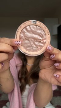 Revolution highlighter i en rund, ljusrosa kompaktförpackning. Har en glänsande, strukturerad yta med präglade mönster. Nettovikt 0,22 oz (6,5 g).