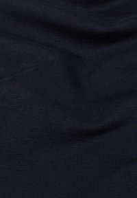 Marineblauwe katoenen stof met een ribbelstructuur, met zachte vouwen en lichte variaties in kleurintensiteit over het oppervlak.