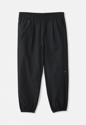 Schwarze, lässige Hose mit elastischem Bund, seitlichen Taschen, elastischen Bündchen an den Knöcheln und einem kleinen Logo am rechten Oberschenkel.