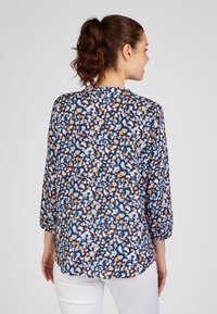 Printed blouse in navy with white, orange, and light blue abstract patterns. Features three-quarter sleeves and a relaxed fit.