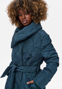 Teal gewatteerde jas met een grote kraag, een ceintuur in de taille en diagonale stiksels. Heeft een zachte textuur en zijzakken.