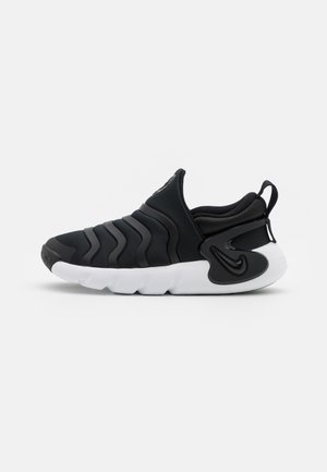 Chaussure de sport noire à enfiler avec un design ondulé sur la tige, semelle blanche épaisse et languette au talon.